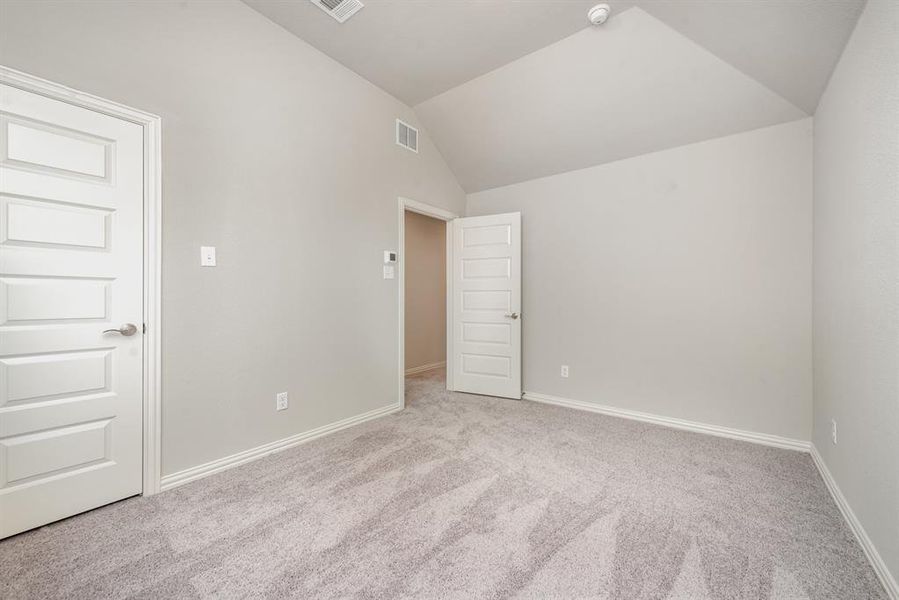 Carpeted empty room with lofted ceiling