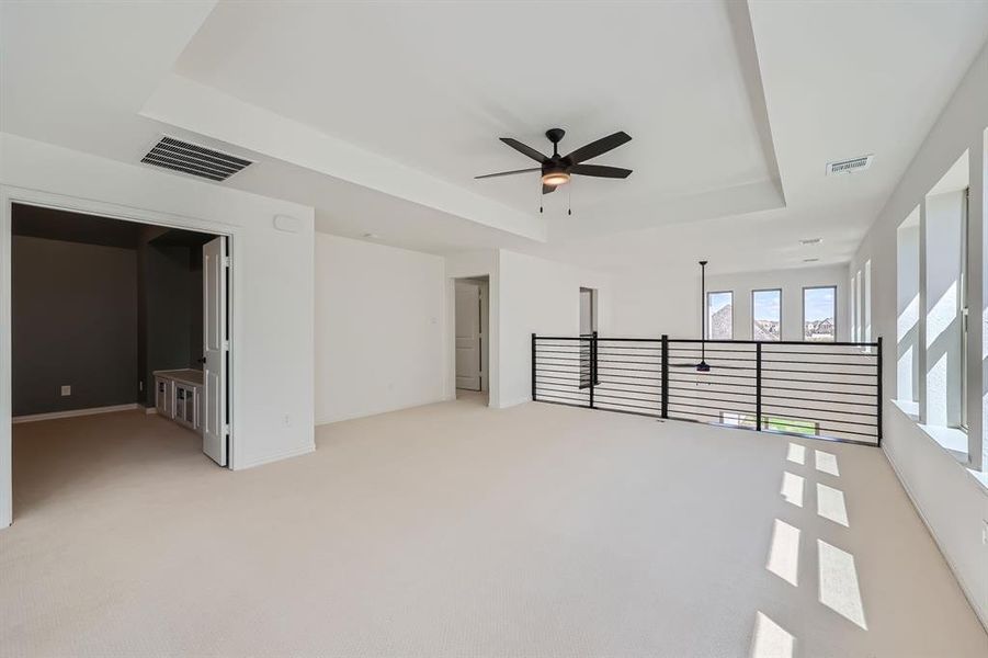 Carpeted empty room featuring ceiling fan and a tray ceiling