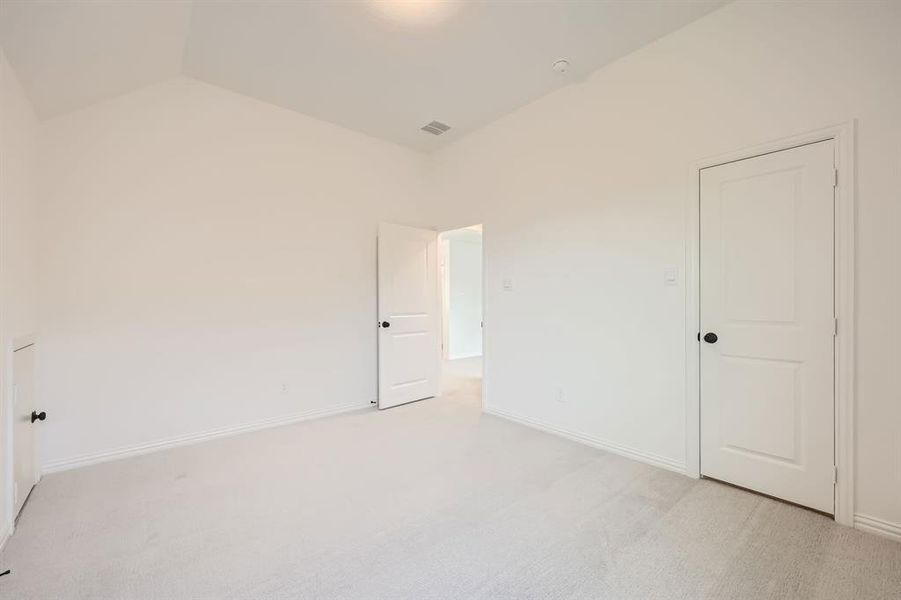 Bedroom with vaulted ceiling and light colored carpet