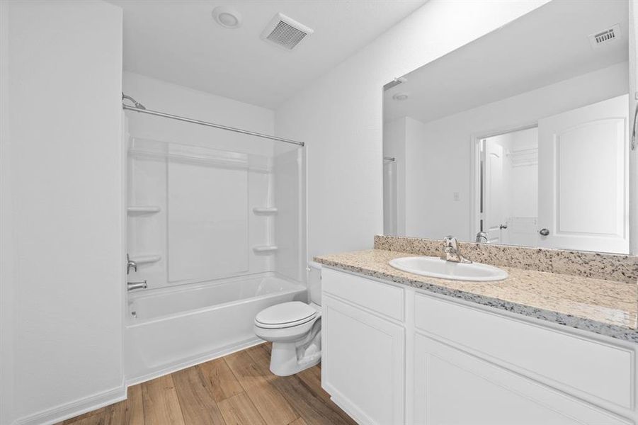 Full bathroom off guest room includes granite counters, designer white cabinetry and luxury vinyl plank flooring.