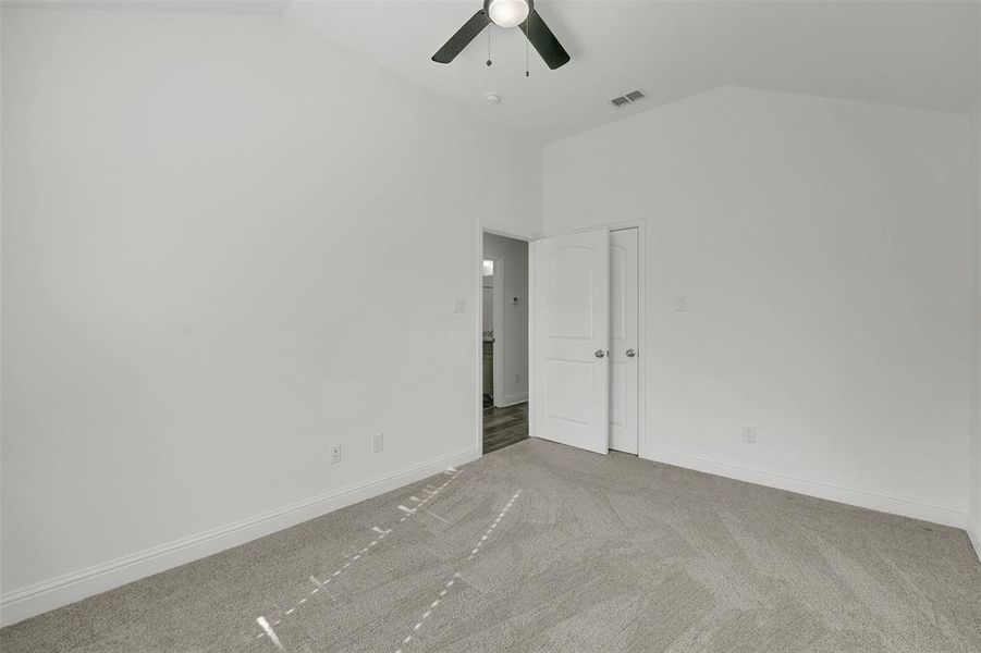 Carpeted spare room with high vaulted ceiling and ceiling fan