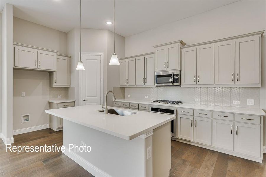 Kitchen with appliances with stainless steel finishes, sink, tasteful backsplash, and dark hardwood / wood-style floors