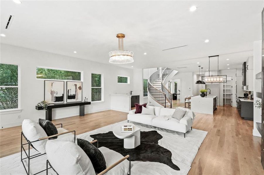 Living room with light hardwood / wood-style floors, a healthy amount of sunlight, and a chandelier