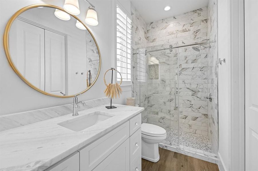 Elegant guest bathroom featuring a sleek walk-in shower and luxurious marble vanity.