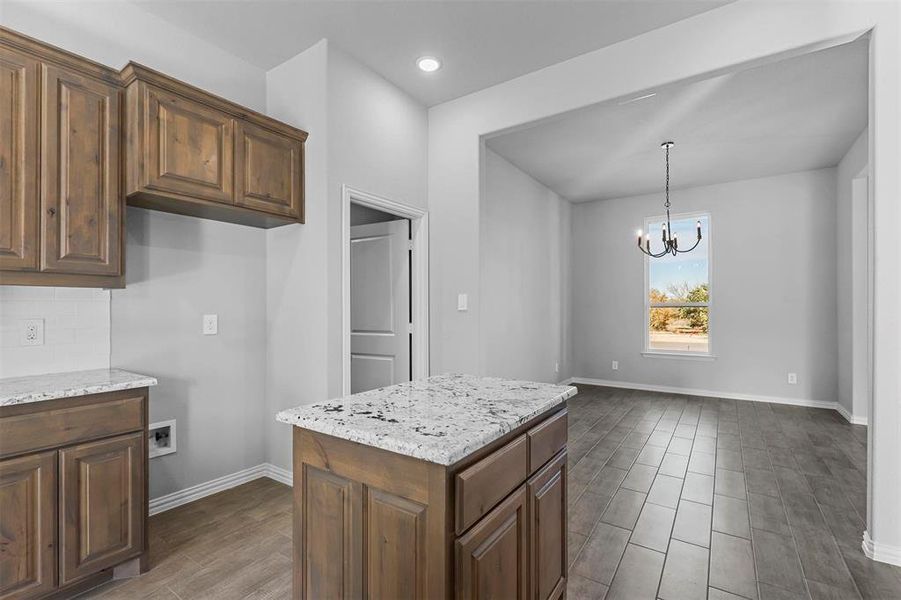 Kitchen with pendant lighting, tasteful backsplash, a chandelier, dark hardwood / wood-style flooring, and light stone counters