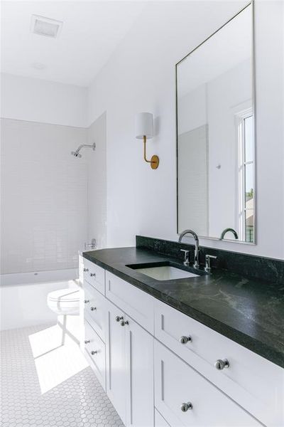 Full bathroom with vanity, tiled shower / bath, toilet, and tile patterned flooring