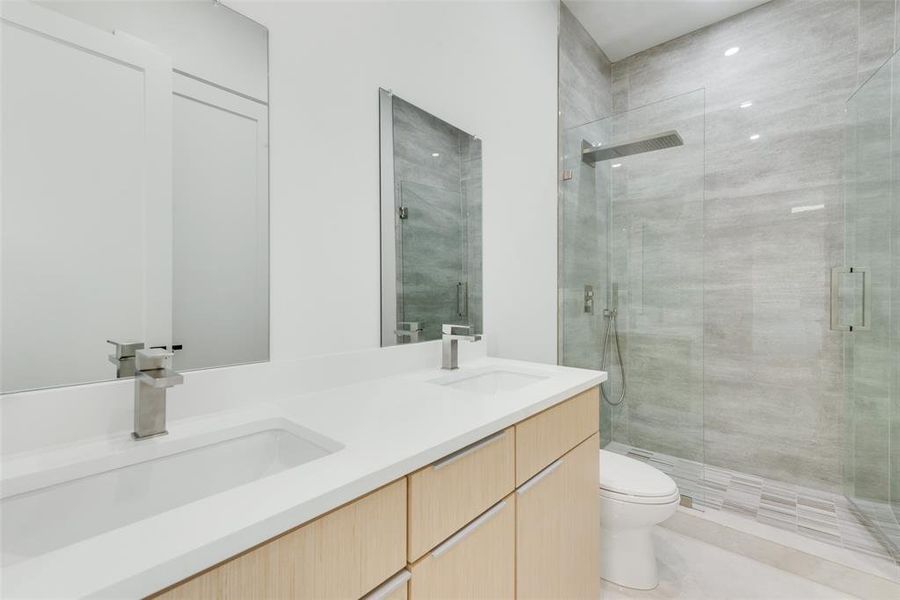 Bathroom with vanity, a shower with shower door, and toilet