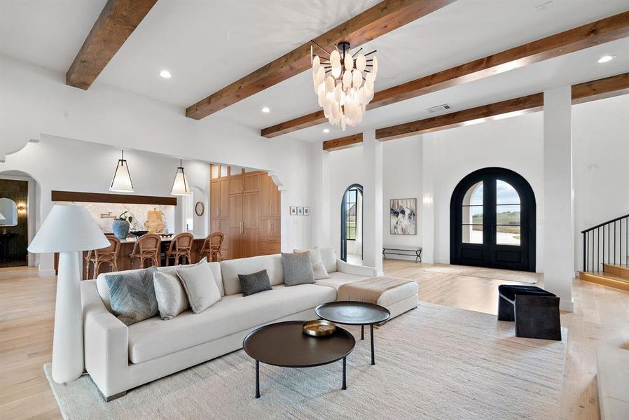 Living room with an inviting chandelier, beamed ceiling, and light hardwood / wood-style flooring