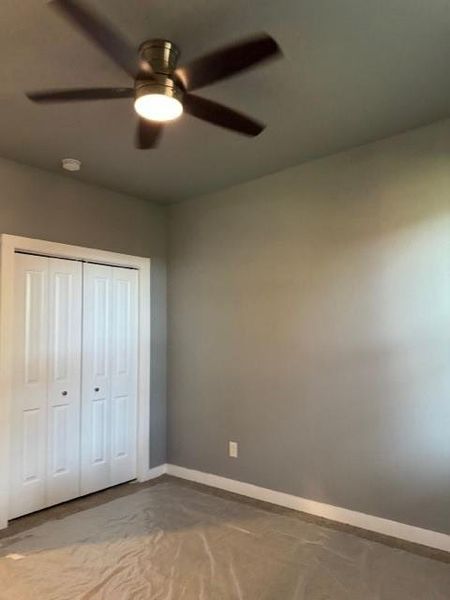 Unfurnished bedroom with ceiling fan and a closet