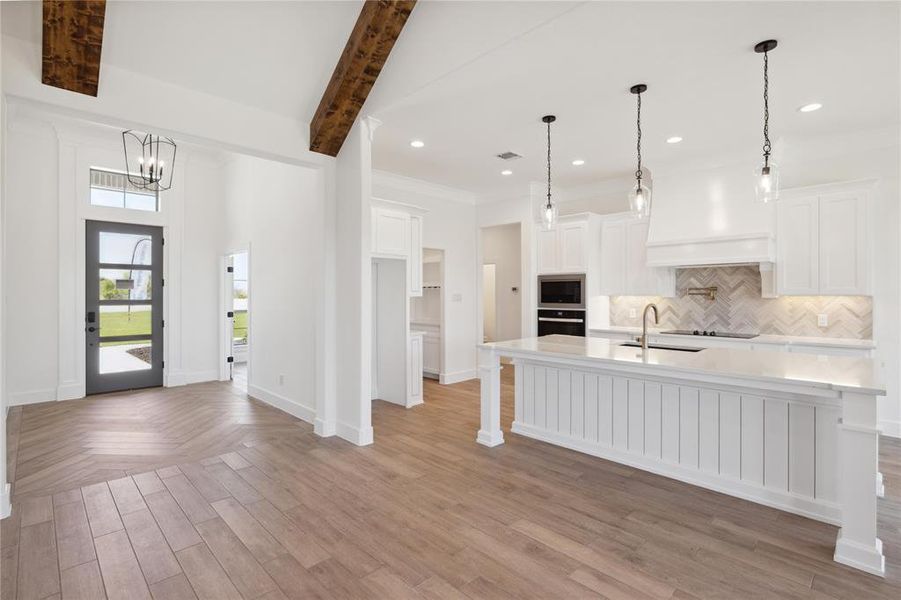 Kitchen with white cabinetry, backsplash, decorative light fixtures, and a breakfast bar area