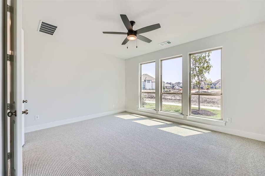 Carpeted spare room featuring ceiling fan and plenty of natural light