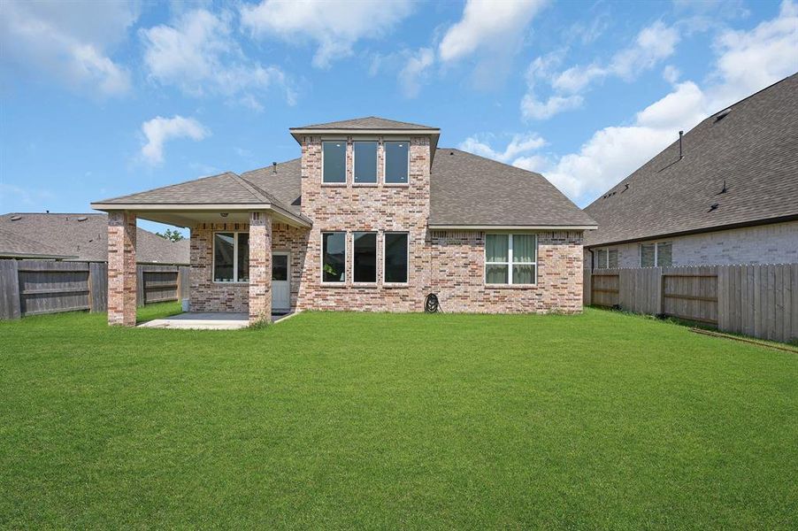 Large fenced backyard featuring a covered patio.