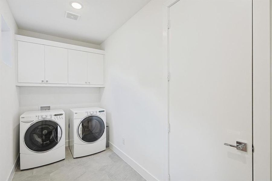 Clothes washing area featuring cabinets and separate washer and dryer