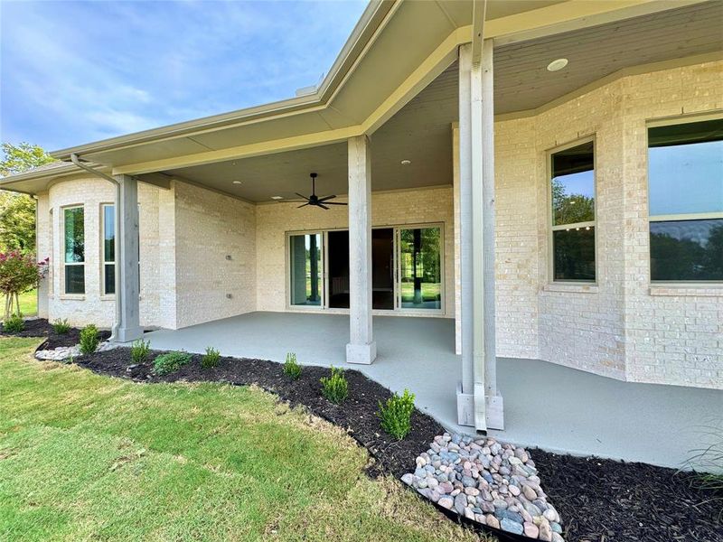 Entrance to property with ceiling fan, a yard, and a patio