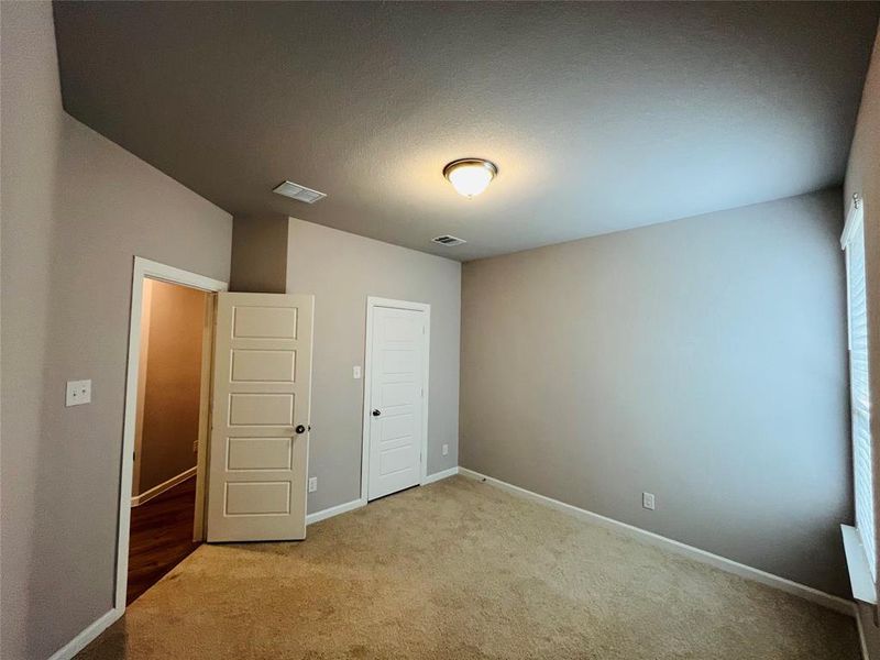 Unfurnished bedroom featuring a textured ceiling, light colored carpet, and a closet