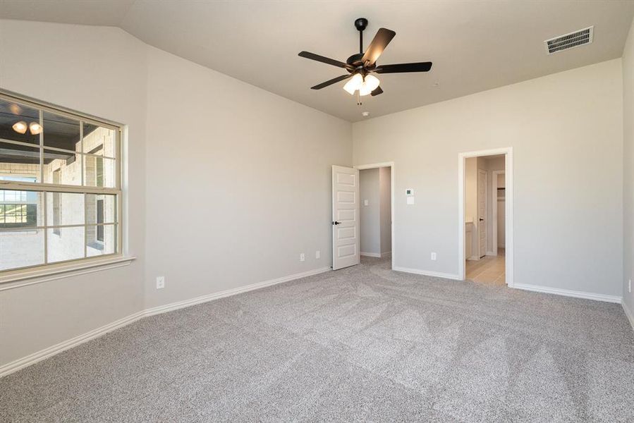 Unfurnished bedroom featuring ensuite bath, light colored carpet, vaulted ceiling, and ceiling fan