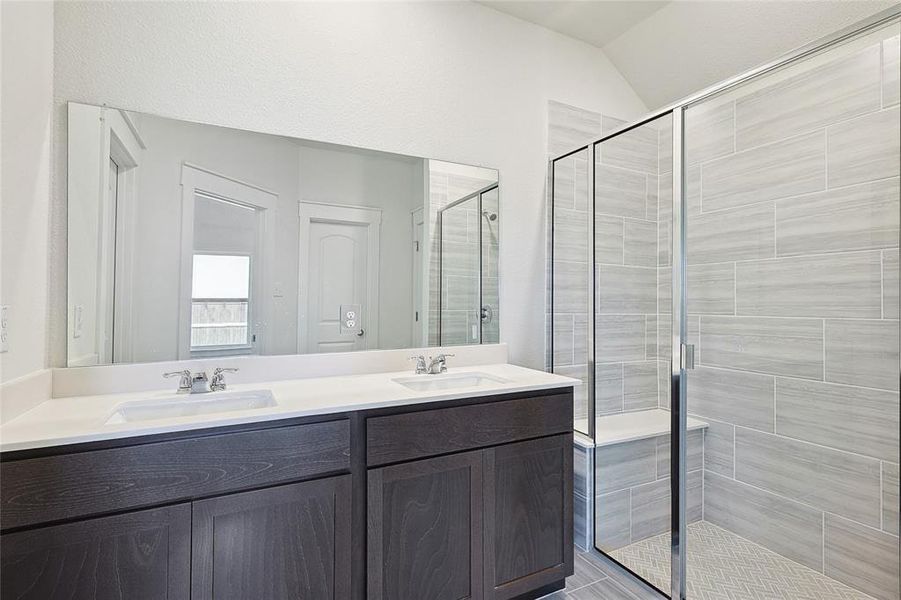 Bathroom with vanity, vaulted ceiling, and walk in shower