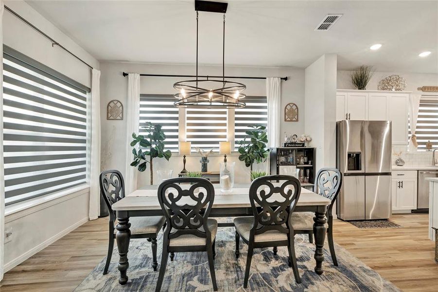 Elegant Dining Space - Spacious and inviting, with upgraded blinds and lighting. The beautiful color scheme and floors create a warm and welcoming dining experience.