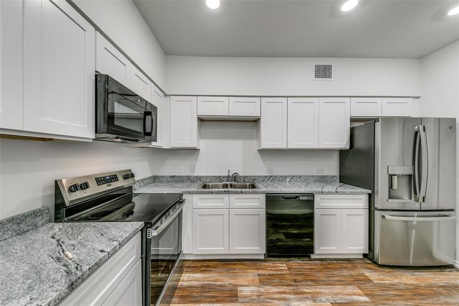 Kitchen featuring black appliances, white cabinetry, sink, and light hardwood / wood-style floors