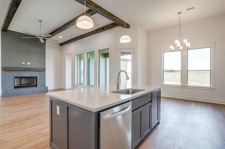 Kitchen with hardwood / wood-style floors, stainless steel dishwasher, an island with sink, gray cabinets, and sink