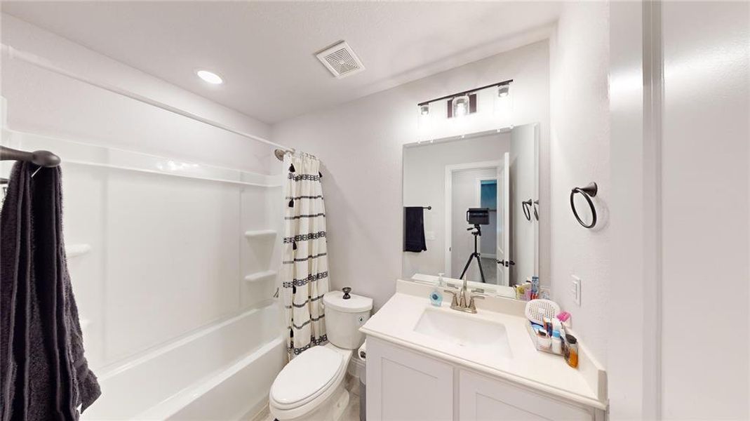 Full bathroom featuring vanity, toilet, and shower / bathtub combination with curtain