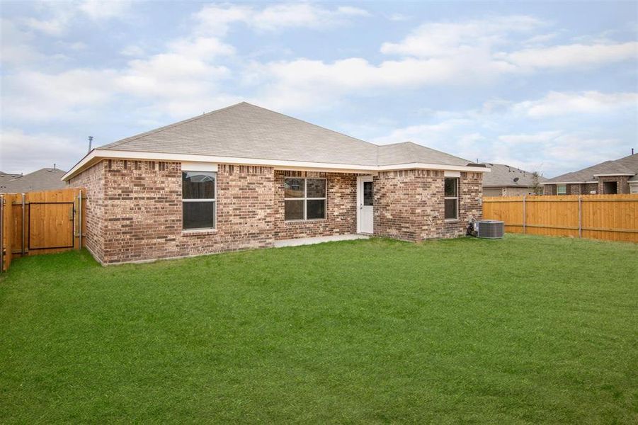 Rear view of house with central AC and a lawn