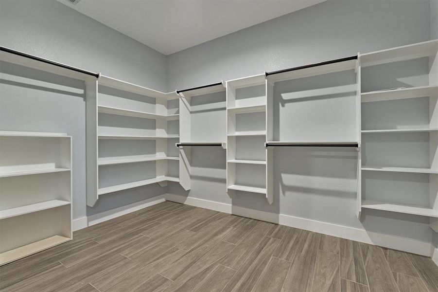 Customized primary closet with plenty of built in hanging space and shelving.