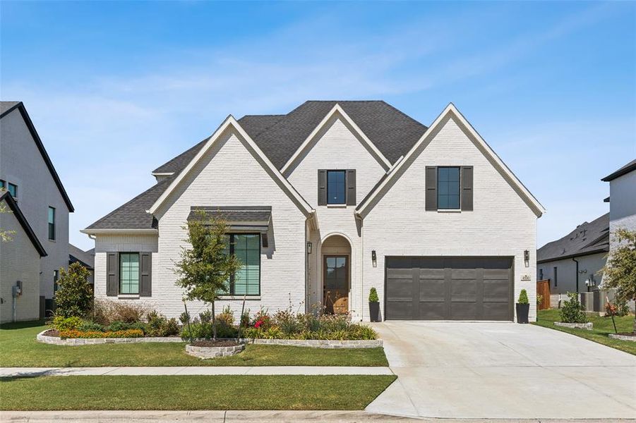 View of front of property featuring a front yard and a garage