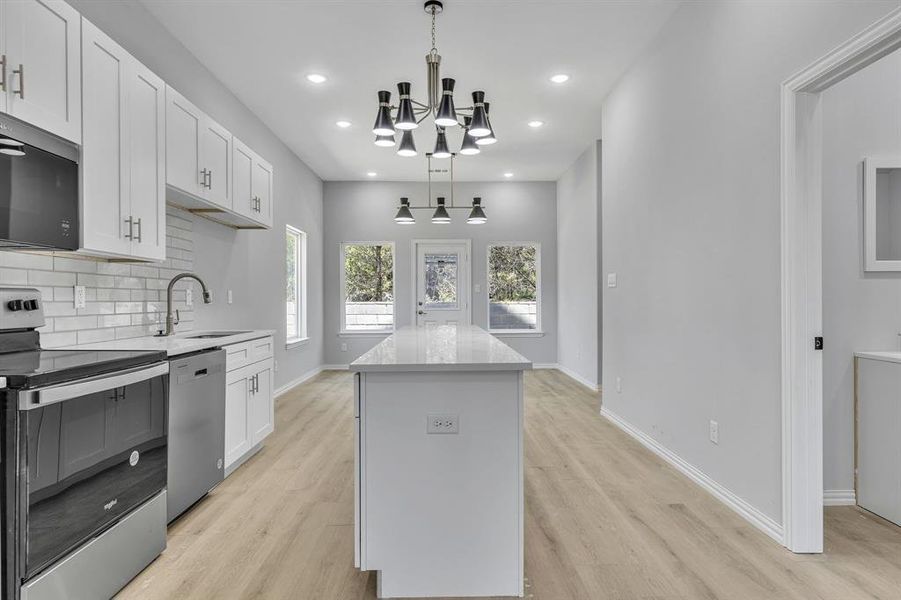 Kitchen with stainless steel appliances, light hardwood / wood-style flooring, sink, and pendant lighting