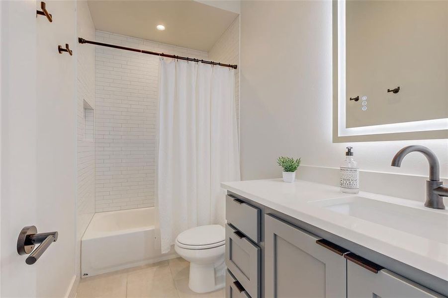 Full bathroom featuring tile patterned floors, toilet, vanity, and shower / tub combo with curtain