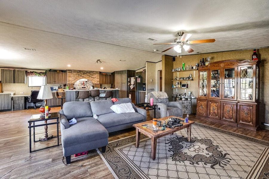 Living room featuring a textured ceiling, ceiling fan, and light hardwood / wood-style flooring