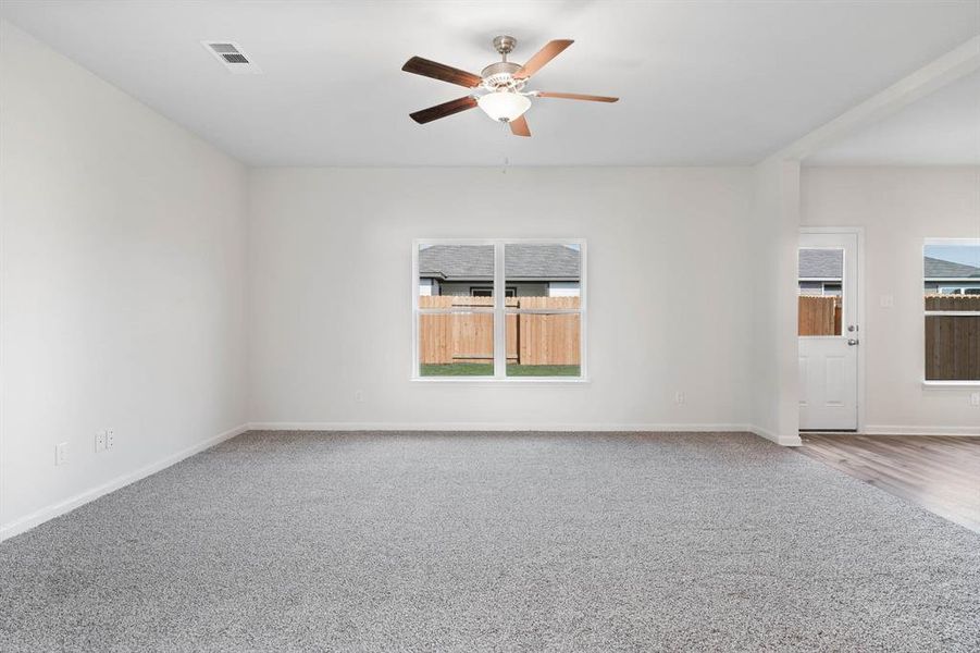 Empty room with carpet flooring, a healthy amount of sunlight, and ceiling fan