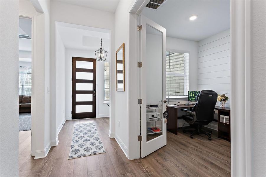 Tall ceilings and luxury vinyl plank floors set the stage as you walk past the well appointed study complete with glass french doors and shiplapped accent wall.