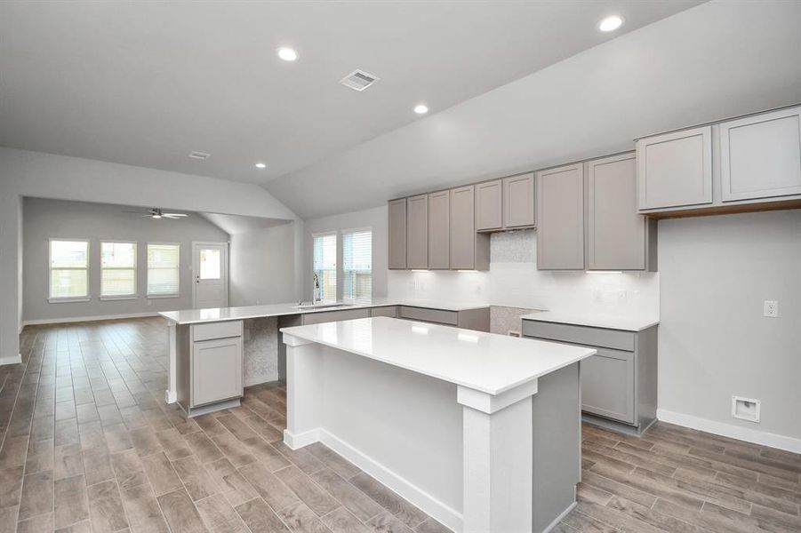 Culinary haven, featuring massive island,  granite countertops, a tile backsplash, stainless steel appliances (to be installed), and 42” upper cabinets. Representation photo. Actual colors and selections may vary.