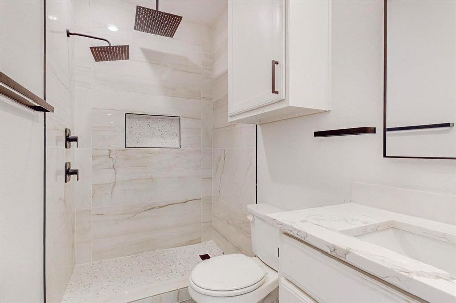 Bathroom with vanity, tiled shower, and toilet