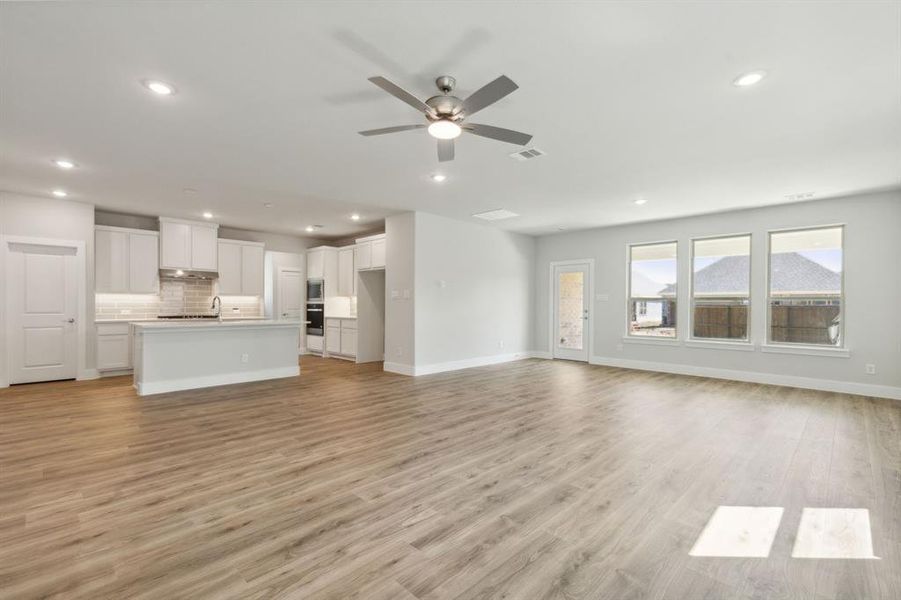 Unfurnished living room featuring ceiling fan, light hardwood / wood-style floors, and sink