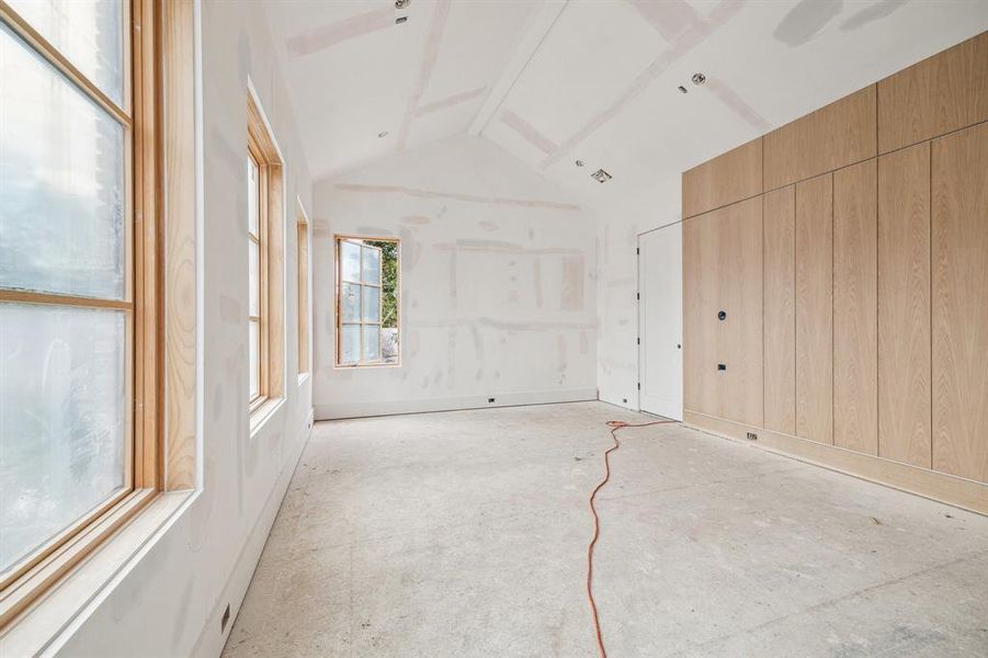 Primary Bedroom with a Cathedral ceiling.  There is a accent wall with White Oak and a consealed door to the Primary Bathroom.