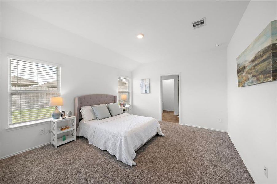 Entering the primary bedroom, located off the hallway, you are greeted with ample space and plenty of natural light.