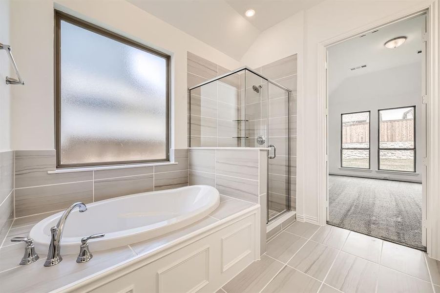 Bathroom featuring plenty of natural light, shower with separate bathtub, lofted ceiling, and tile patterned floors