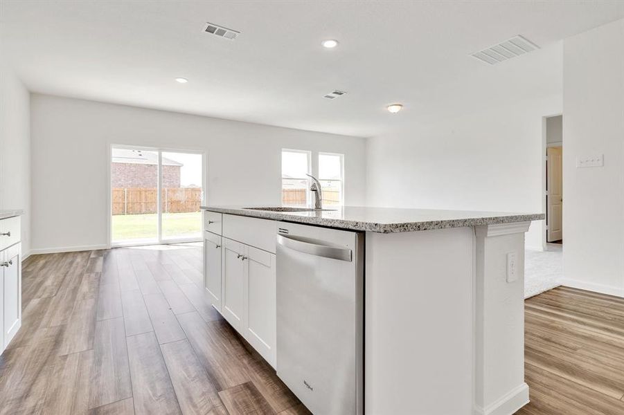 Kitchen featuring dishwasher, sink, an island with sink, and plenty of natural light