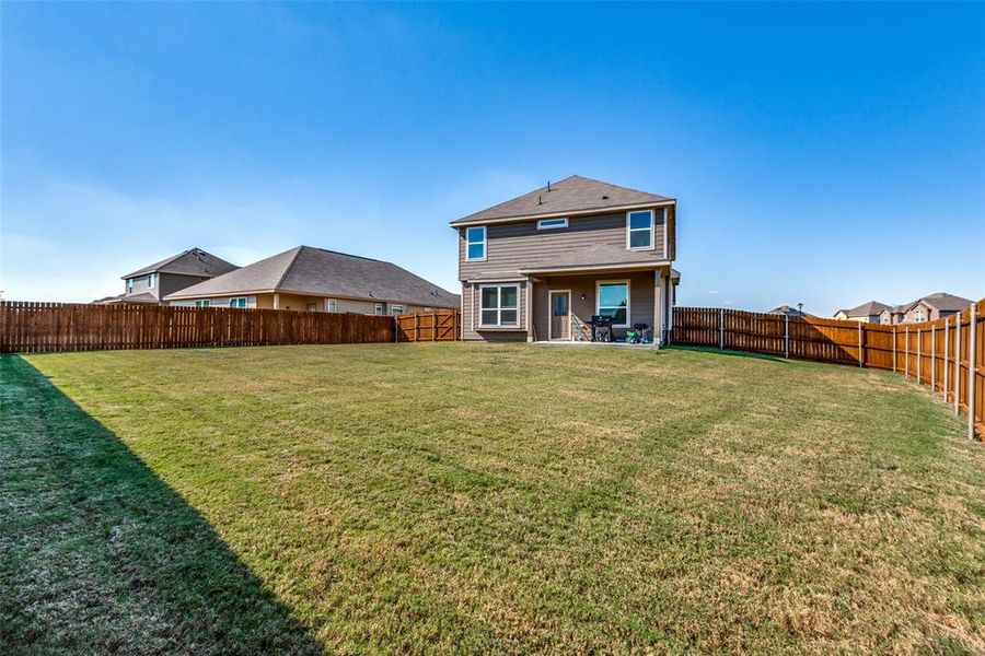 Back of house with a lawn and a patio