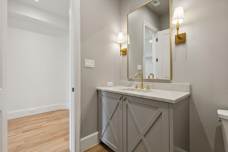 Half bathroom featuring vanity, hardwood / wood-style floors, and toilet