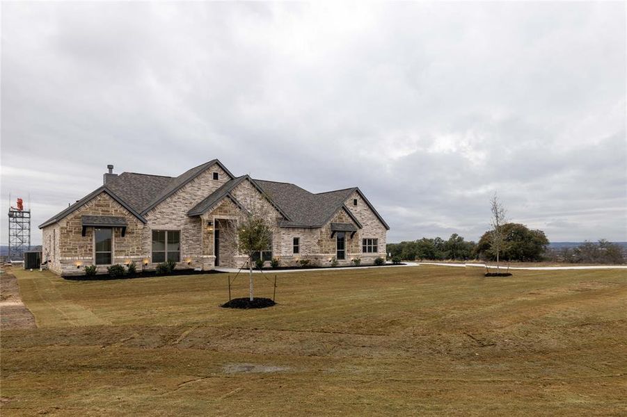 French country inspired facade featuring a front yard and central air condition unit