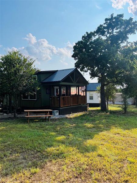 Rear view of property featuring central AC unit and a lawn