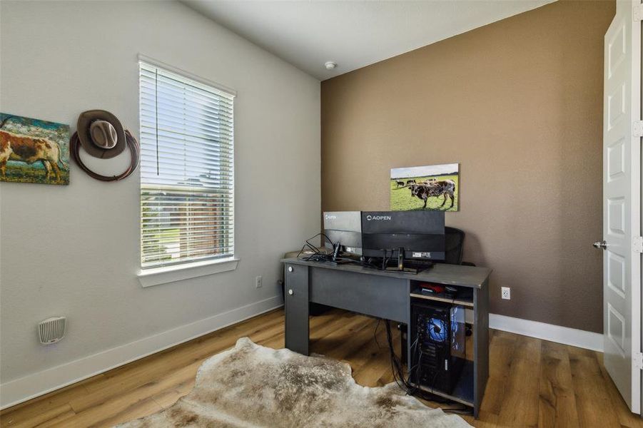 Home office with wood-style floors and double solid panel doors.