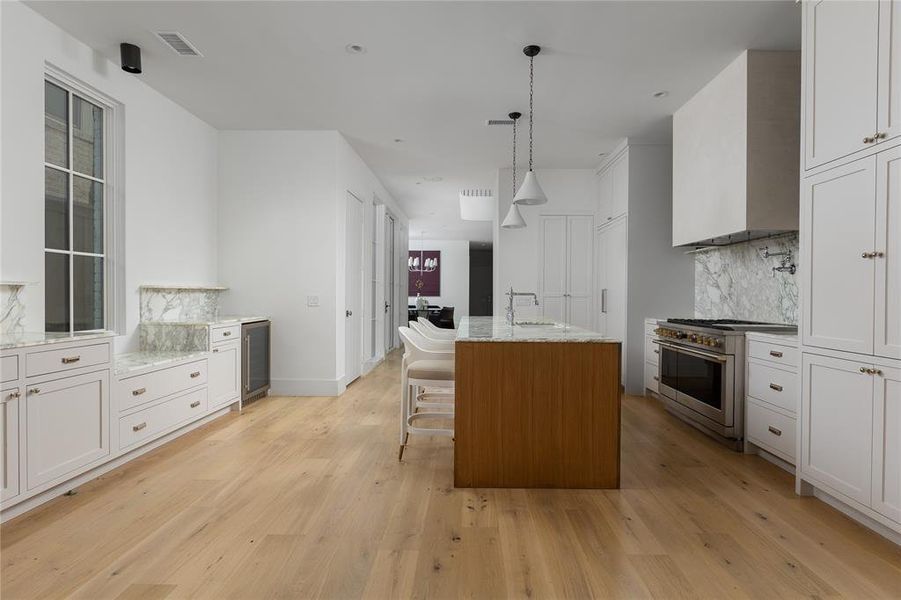 Kitchen featuring backsplash, premium stove, white cabinetry, and light wood-type flooring
