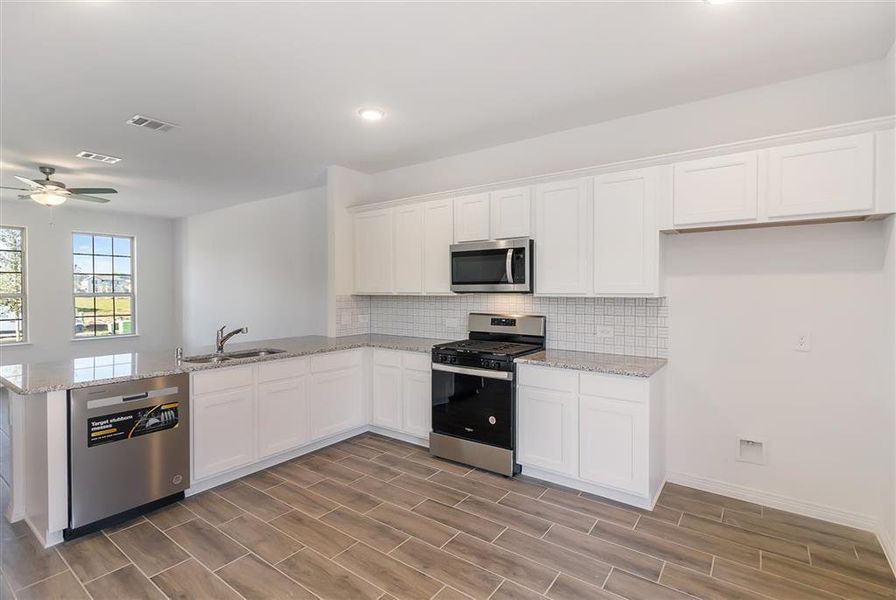 The kitchen offers upgraded modern backsplash, granite and stainless steel Whirlpool appliances.