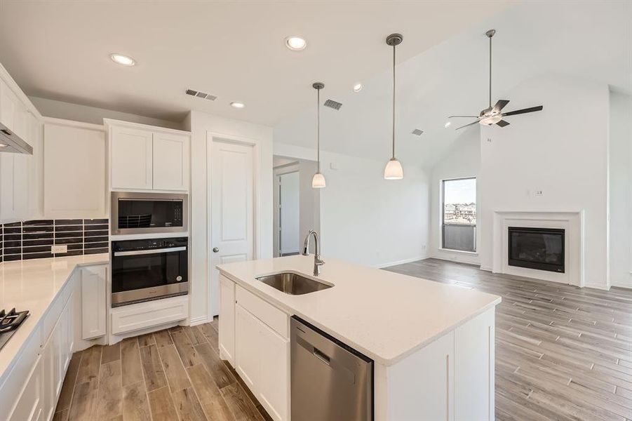 Kitchen with white cabinetry, stainless steel appliances, sink, and an island with sink