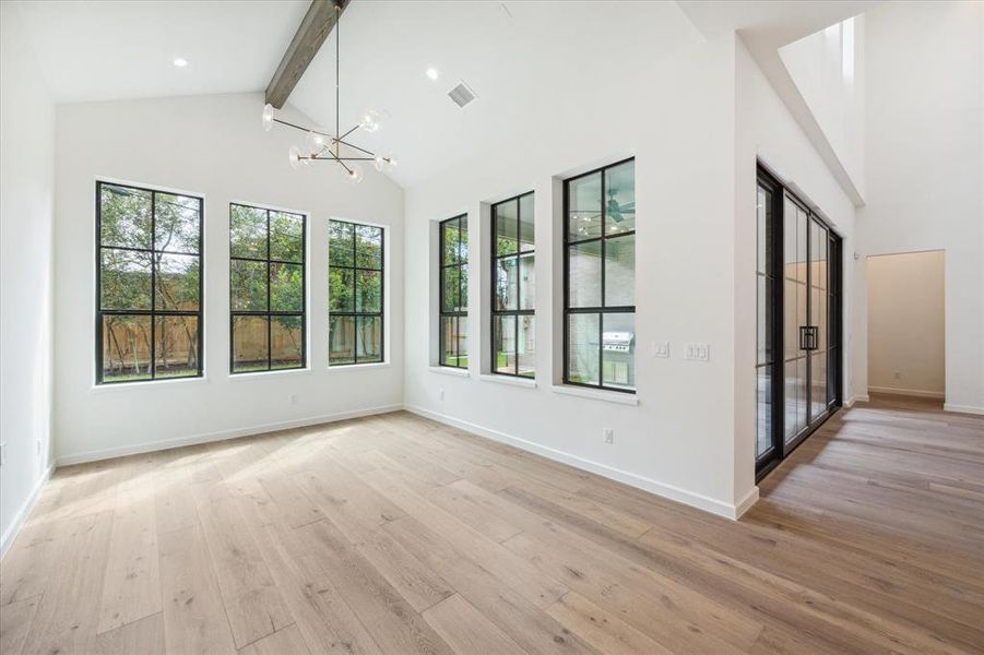 The spacious dining area features an elegant chandelier, vaulted ceiling, and large windows, allowing for both natural light and privacy.