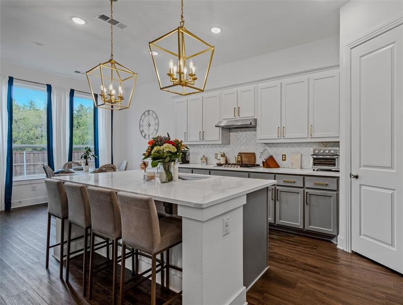 Kitchen with a kitchen breakfast bar, a kitchen island with sink, decorative light fixtures, and dark hardwood / wood-style flooring